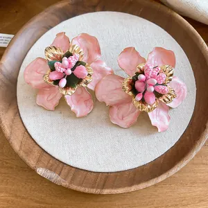 Detailed close-up showing the glossy pink enamel and gold petals of these flower earrings.