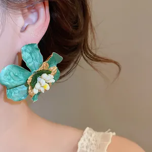 Vintage teal enamel flower earring macro detail on model's ear for luxury style.