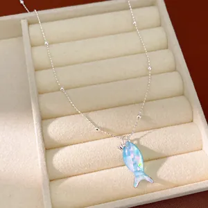 Detail van een zilveren ketting met een prachtige blauw iriserende visvormige hanger.