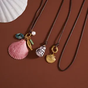 Macro view of ocean-themed necklaces with pink and golden shell charms on brown background