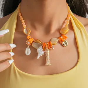 Gros plan d'un collier bohème orange avec des breloques de coquillage et de poisson