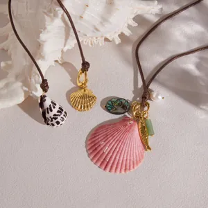Close-up detail of luxury necklaces featuring natural shell pendants and gold-toned charms.