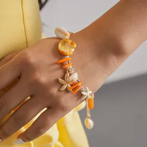 Vue détaillée d'un bracelet de vacances d'été avec breloques coquillage et étoile de mer au poignet