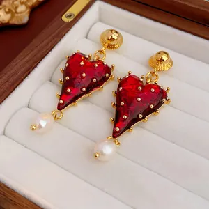 Close-up of vintage-style red heart earrings with pearl drops in a jewelry box