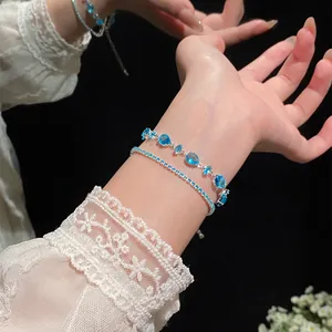 Elegant layered adjustable bracelets with light blue zircons on a wrist with lace