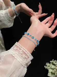 Detail view of blue zircon adjustable bracelets on a wrist with elegant lace sleeves.