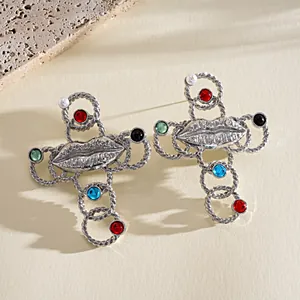 Close-up of retro metallic lip cross earrings with colorful resin stones and pearls