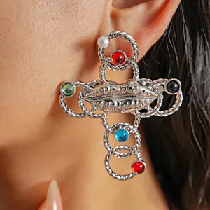 Detailed view of vintage silver cross earrings with colorful resin stones and lip accent