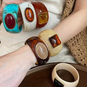 Close-up of bohemian style acrylic bracelets with colorful gradient resin stones and gold borders