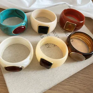 Close-up of colorful acrylic bangles with square resin details on linen background