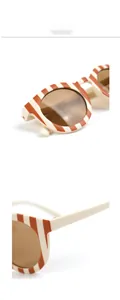 Close-up detail of stylish orange and white striped children sunglasses with brown lenses