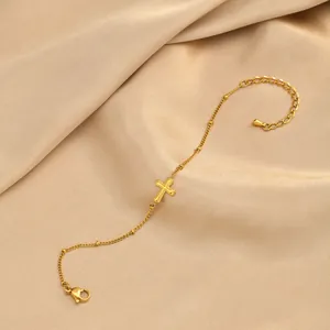 Gros plan détaillé d'un bracelet croix en acier inoxydable plaqué or 18 carats sur soie