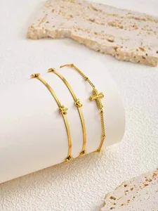 Détail de bracelets en acier inoxydable plaqué or 18 carats avec croix et cœurs