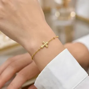 Gros plan d'un bracelet en acier inoxydable doré 18 carats avec pendentif en croix