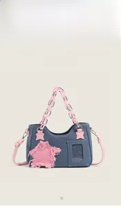 Detail of denim handbag featuring pink star patch, clear card slot, and plastic chain strap