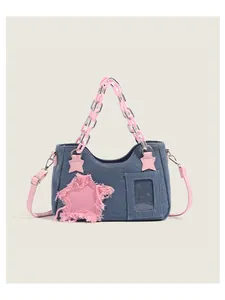 Detail of denim tote bag with pink star patch, transparent window and chain handle