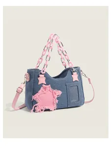 Detail of denim bag featuring a pink frayed star patch and transparent card window