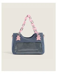 Close-up of blue denim handbag featuring pink star patches and metallic chain handle