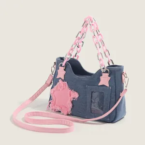 Blue denim tote bag with pink star patch and plastic chain strap on white background