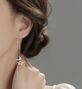 Close-up view of elegant silver star and moon tassel ear line earrings worn by a model