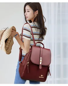 Close-up of a stylish burgundy leather backpack worn by a model in a bright room