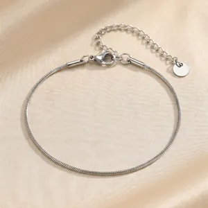 Close-up view of a sleek silver stainless steel snake chain bracelet on silk fabric
