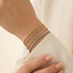 Detailed close-up of four minimalist stainless steel round snake chain bracelets