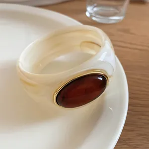 Detailed view of cream marble acrylic bracelet featuring a large oval amber resin stone