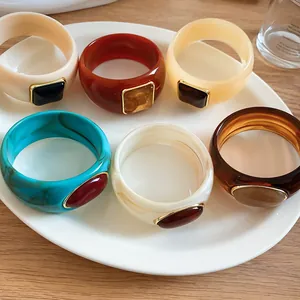 Vibrant bohemian acrylic bangles with embedded gemstone accents on a white plate