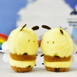Detailed macro shot of two cute fuzzy yellow bee plush keychains with soft textures.