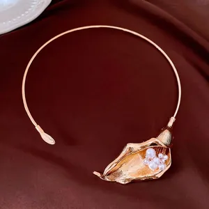 Elegante girocollo a giglio calla dorato con accenti di perle su sfondo di tessuto marrone