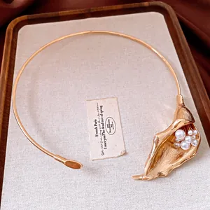 Dettaglio di una collana con ciondolo a giglio calla dorato e perle su un vassoio