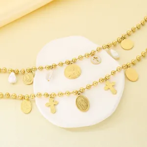 Détail du collier en acier titane doré avec breloques religieuses et perles baroques