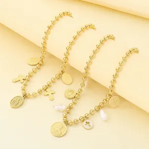 Détail de colliers dorés à perles avec des médaillons religieux et perles baroques.
