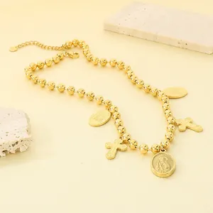 Vue détaillée d'un collier à billes dorées avec des breloques de croix et de madone