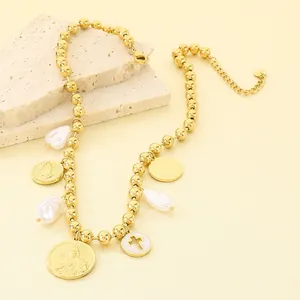 Détail d'un collier vintage en acier titane avec breloques religieuses et perles baroques