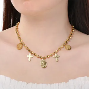 Gros plan d'un collier vintage doré avec des médailles religieuses et des croix.