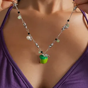 Detailed close-up of a vibrant green apple necklace featuring stars and pearls beads