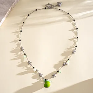 Detailed view of a sweet enamel apple necklace featuring silver stars and pearls.