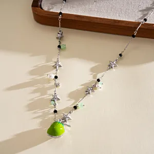 Close-up detail of a sweet enamel green apple necklace with stars and elegant pearls
