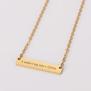 Vue détaillée de la gravure 'A mother's hug lasts a lifetime' sur collier barre en or