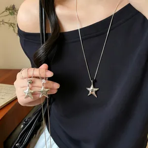 Detail view of Korean style silver star pendant necklaces on a black top.