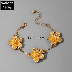 Detailed macro view of textured gold flower charms on an adjustable anklet chain