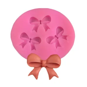 Pink silicone mold featuring three bow shapes with a finished fondant bow sample
