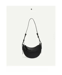 Macro detail of black lychee grain leather on a crescent hobo shoulder bag
