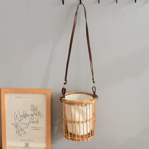 Detail of a handcrafted rattan bucket bag featuring a brown leather shoulder strap