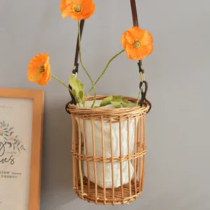 Detail view of a rustic handwoven rattan hanging flower basket with leather straps