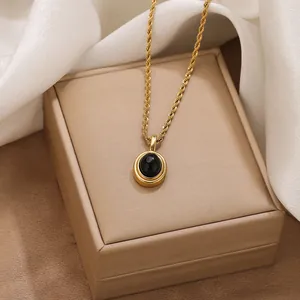 Close-up detail of a retro golden rope chain necklace with an oval black stone pendant