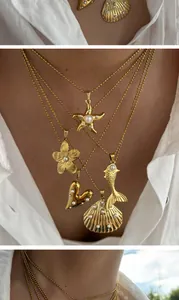 Close-up of elegant gold sea-themed and heart pendants with pearl inlay on ball chains