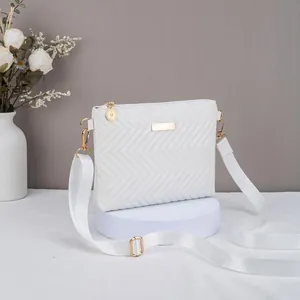 Elegant white quilted crossbody bag with gold metal bar accent and wide adjustable strap